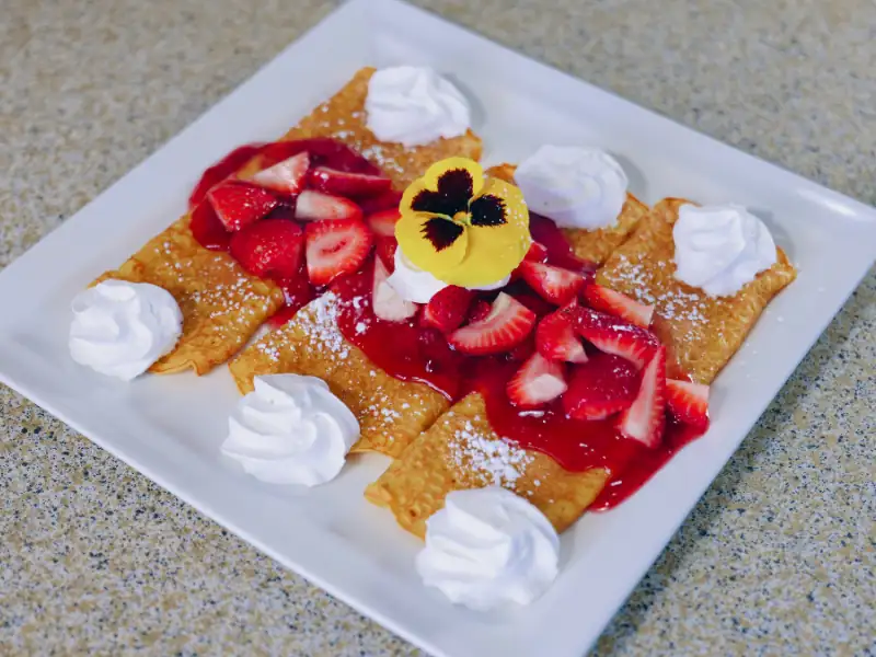 Fresh strawberries, powdered sugar & whipped cream atop of three crepes.