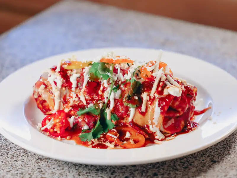 Burrito with steak, scrambled eggs and smothered in spanish sauce and sour cream.